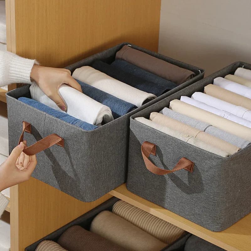 Dois cestos na prateleira do guarda-roupa, um com calças jeans e outro com camisas